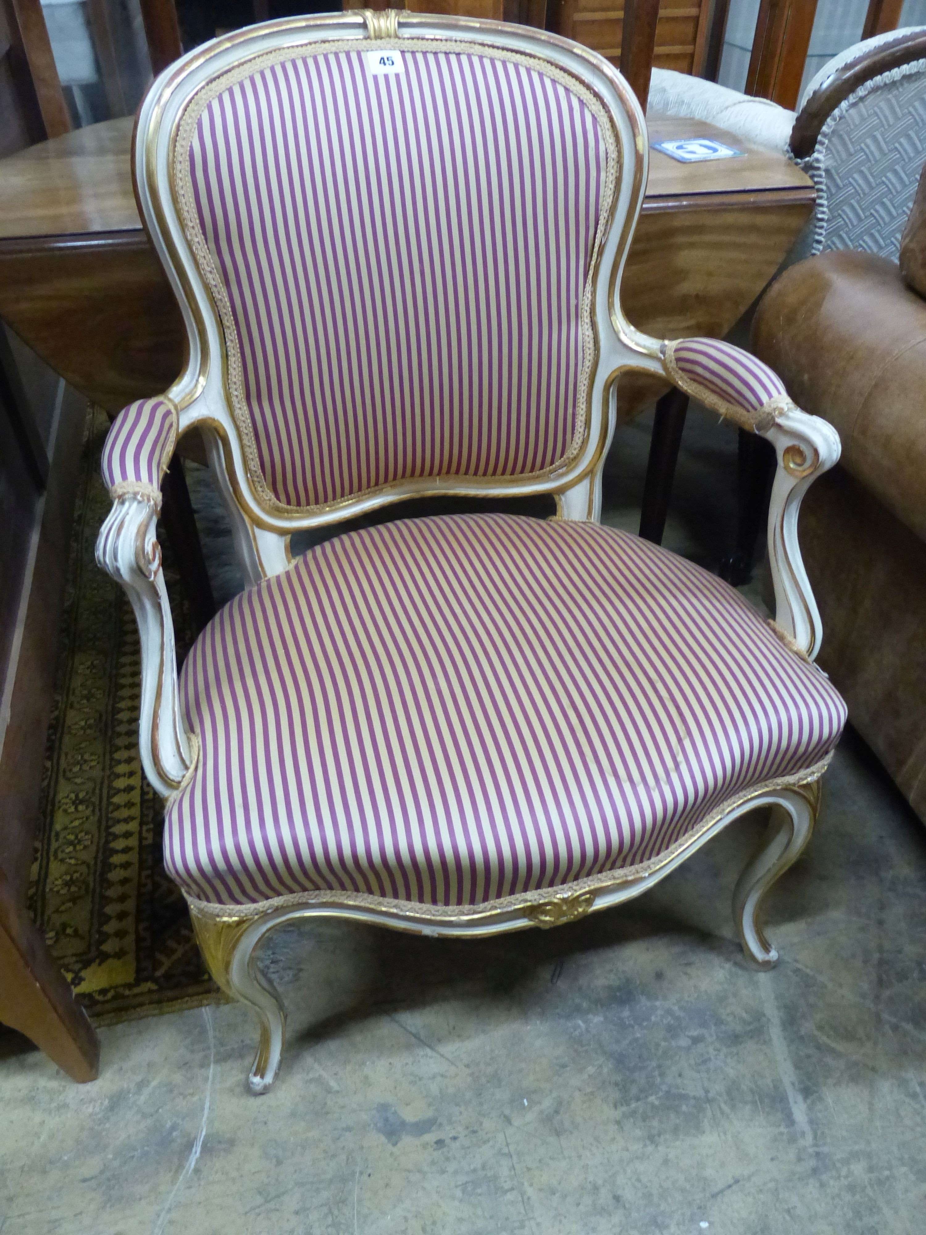 A 19th century French Louis XV style parcel gilt, cream painted fauteuil, with striped upholstery.